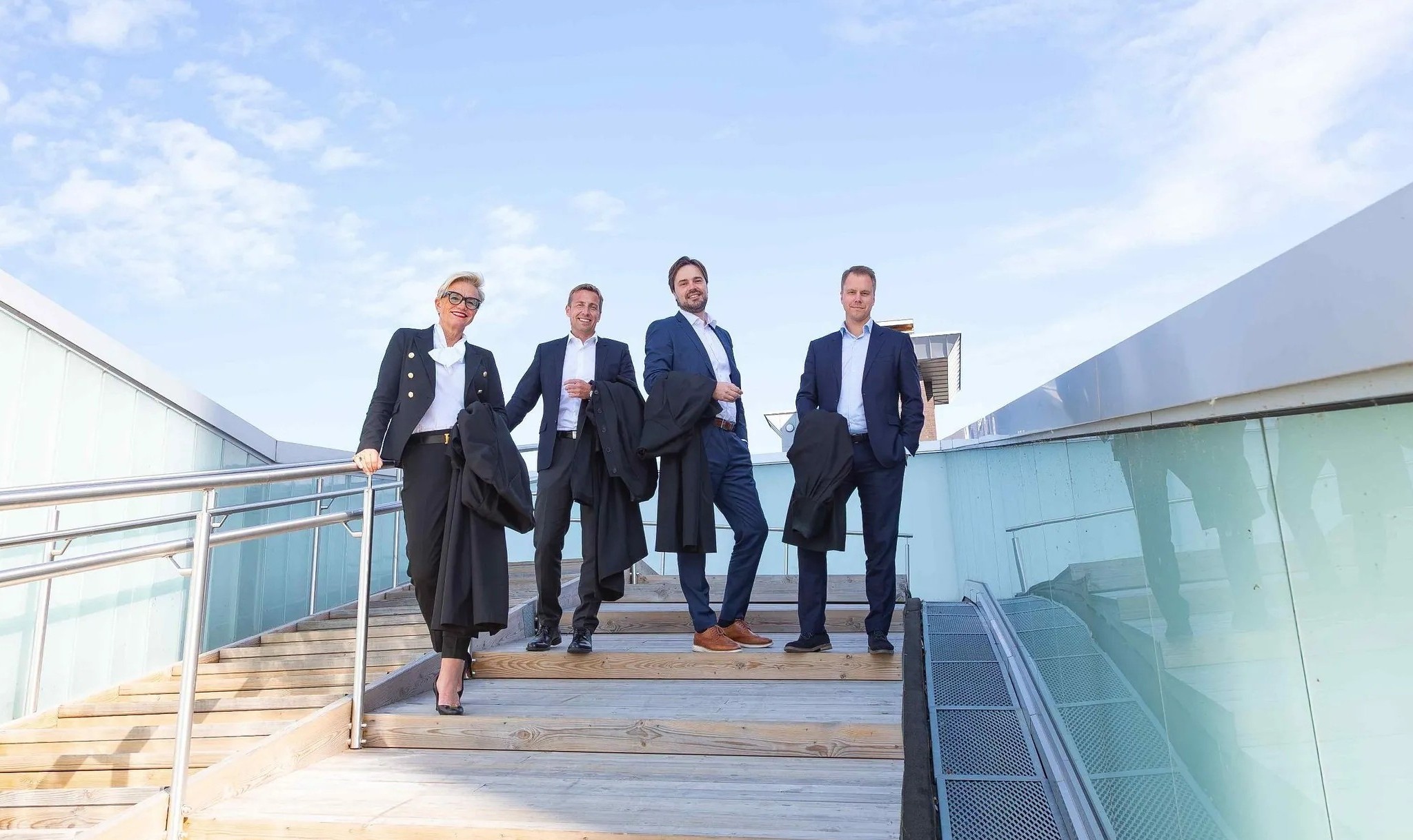 Advokatene Gunhild Lærum, Gard A. Lier, Simon L. Stende og André Berven med blå himmel i bakgrunnen.