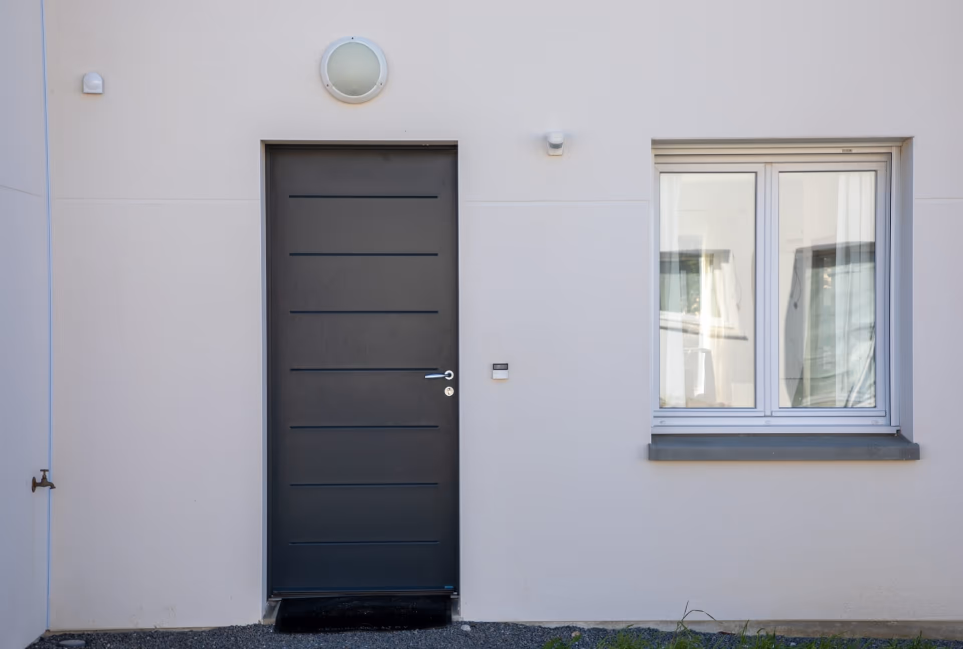 Dark grey aluminum door with horizontal lines, silver handle, and light-coloured exterior.