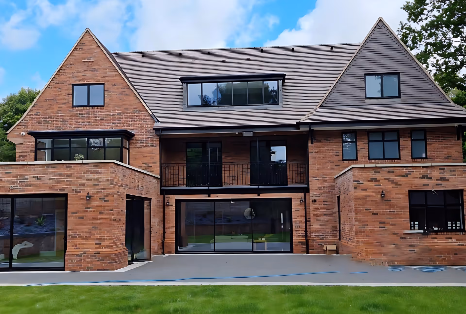 Modern brick house with large sliding glass patio doors opening onto an outdoor area, allowing natural light into the ground floor rooms.