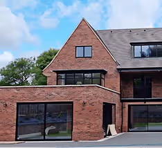 Modern UPVC conservatory with large windows and French doors on a brick base, showcasing upvc doors and windows suppliers.