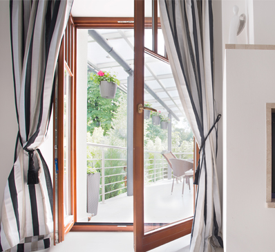 Modern glass conservatory with white-framed windows and doors on a brick home, highlighting window and door manufacturers.