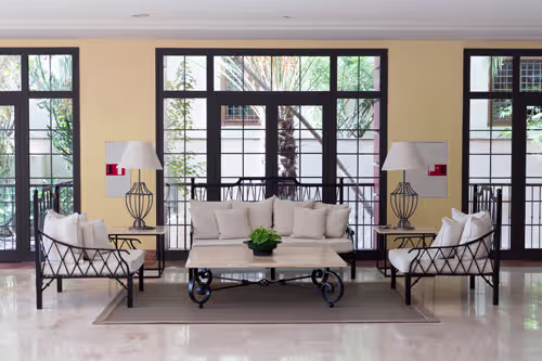 A green couch in front of a city view through uPVC casement windows, blending comfort with urban elegance.