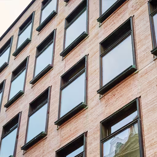 Red brick building with double glazed windows, framed by a vibrant sunset in the background.