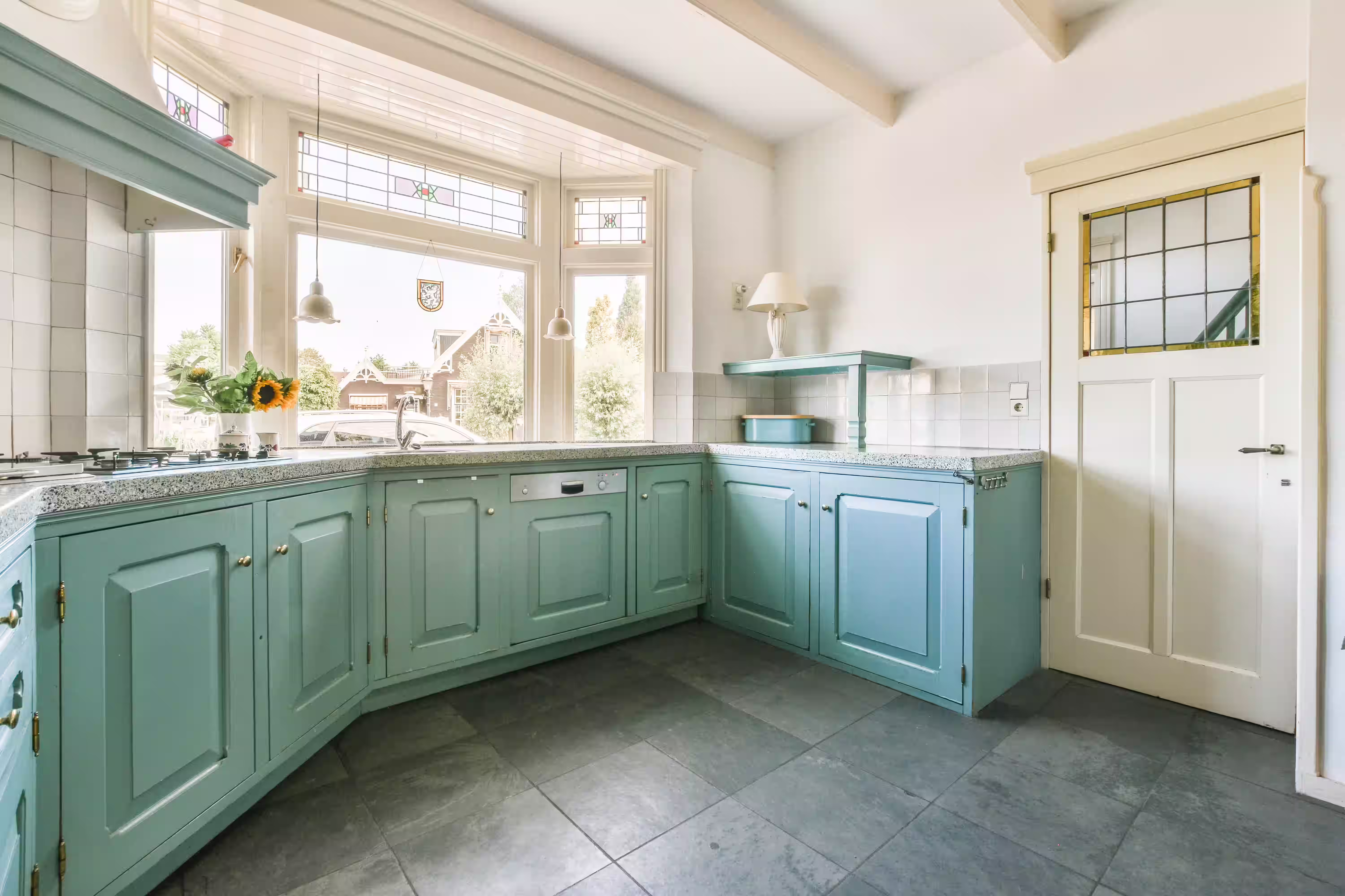 Bright kitchen featuring a large window and wooden floor, showcasing elegant bay and bow windows for natural light.