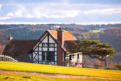 A charming stone house featuring green shutters and a matching green door, embodying classic country home aesthetics.