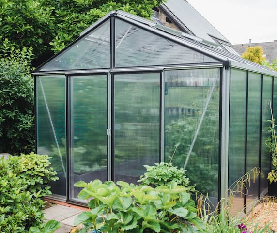 Bright sunroom featuring wicker furniture and lush plants, ideal for a conservatory installation to enhance your home.