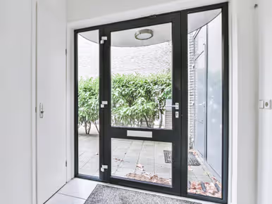 A towel rests on a window sill as rain falls outside, highlighting the charm of heritage aluminium doors in UK homes.