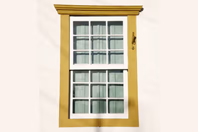 White window with gold trim, showcasing a classic heritage design in traditional sliding sash style.