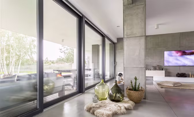 Minimalist interior with wooden dining set and sliding glass doors, offering a bright open-plan layout and seamless connection to outdoor space.