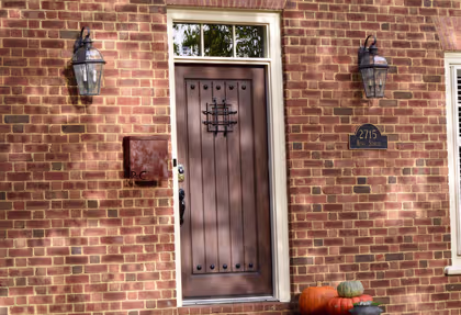 A stylish black door framed by a white porch and vibrant potted plants, showcasing lasting appeal and charm.