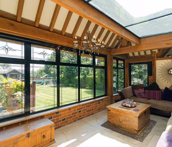 Newly built conservatory with large glass panels and dark roof, showcasing ongoing interior work with visible construction materials.