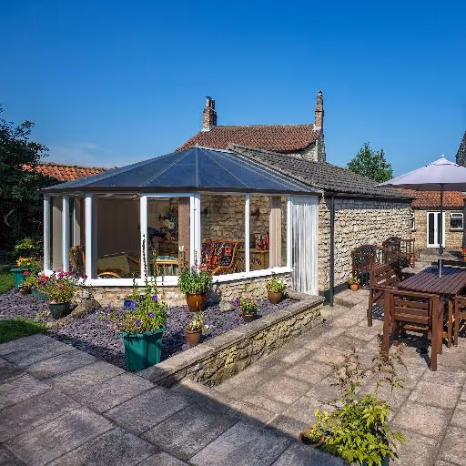 Brick house with an elegant conservatory featuring large windows and a sloped glass roof