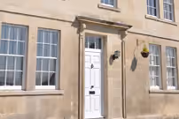 Building with two vertical windows and white door in a conservation area