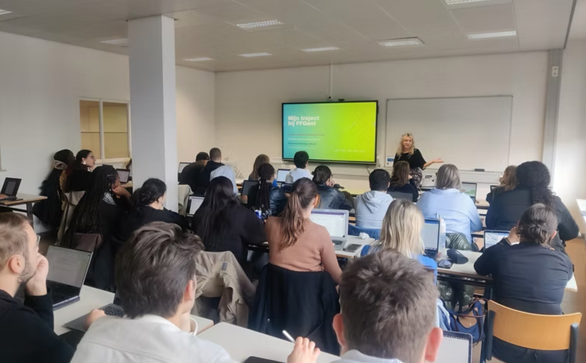 Jasmin geeft een workshops. Ze staat voor een klas vol studenten.
