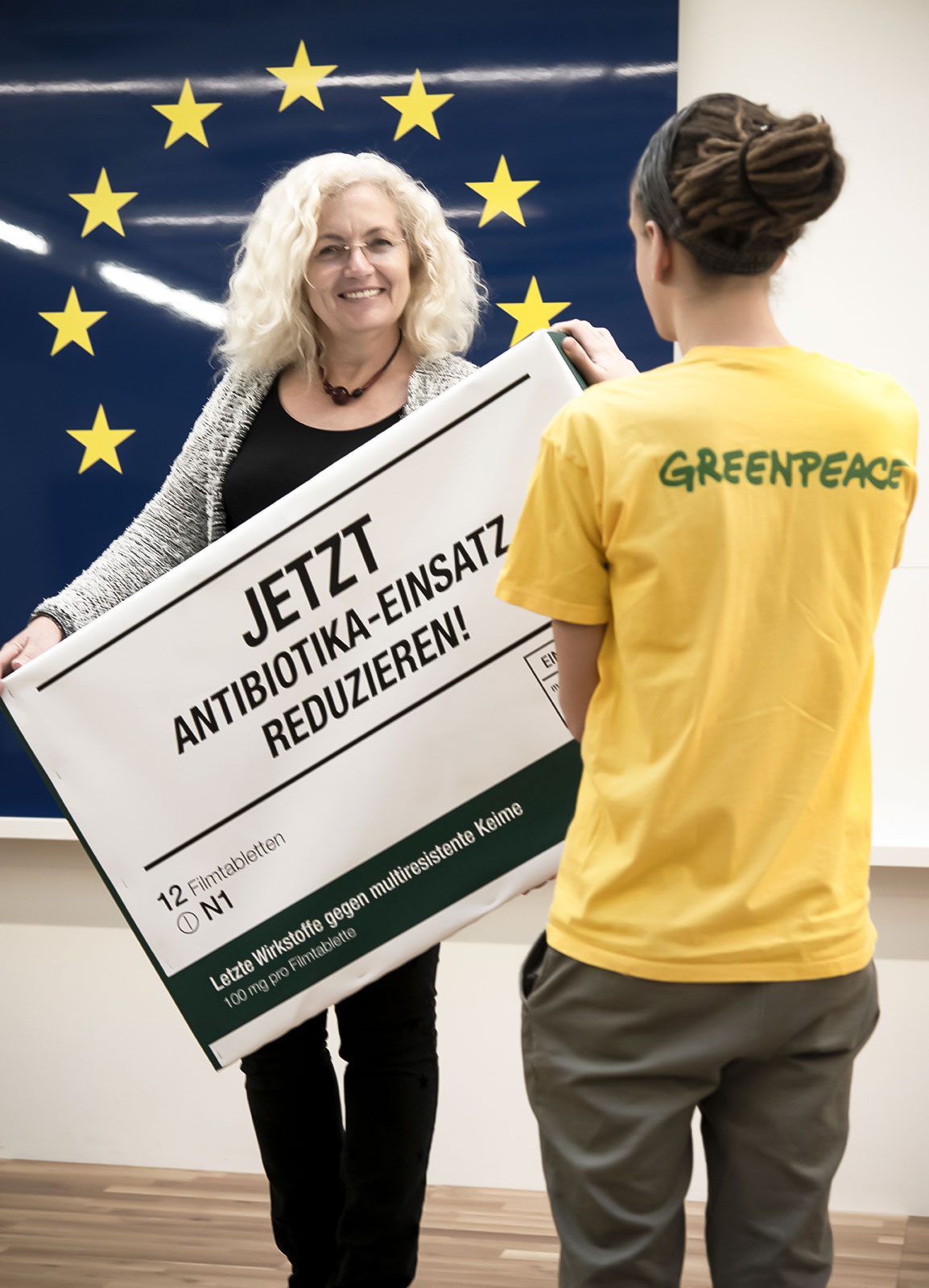 Picture showing a representative of Greenpeace together with Karin Kadenbach, former member of the European Parliament. They are holding an oversized medicine box to the camera: reduce the use of antibiotics now.