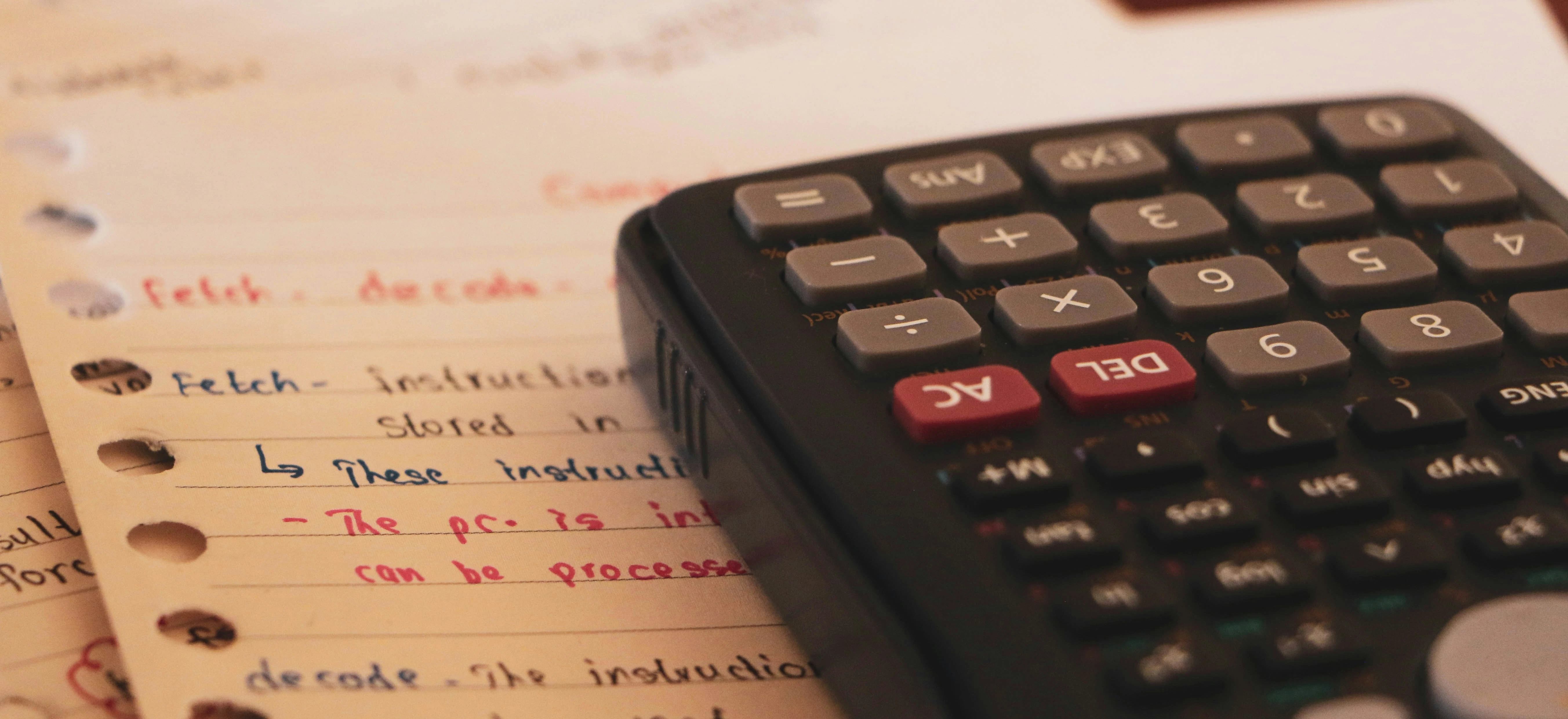 A close-up of a calculator on handwritten notes, showing financial calculations and accounting work.