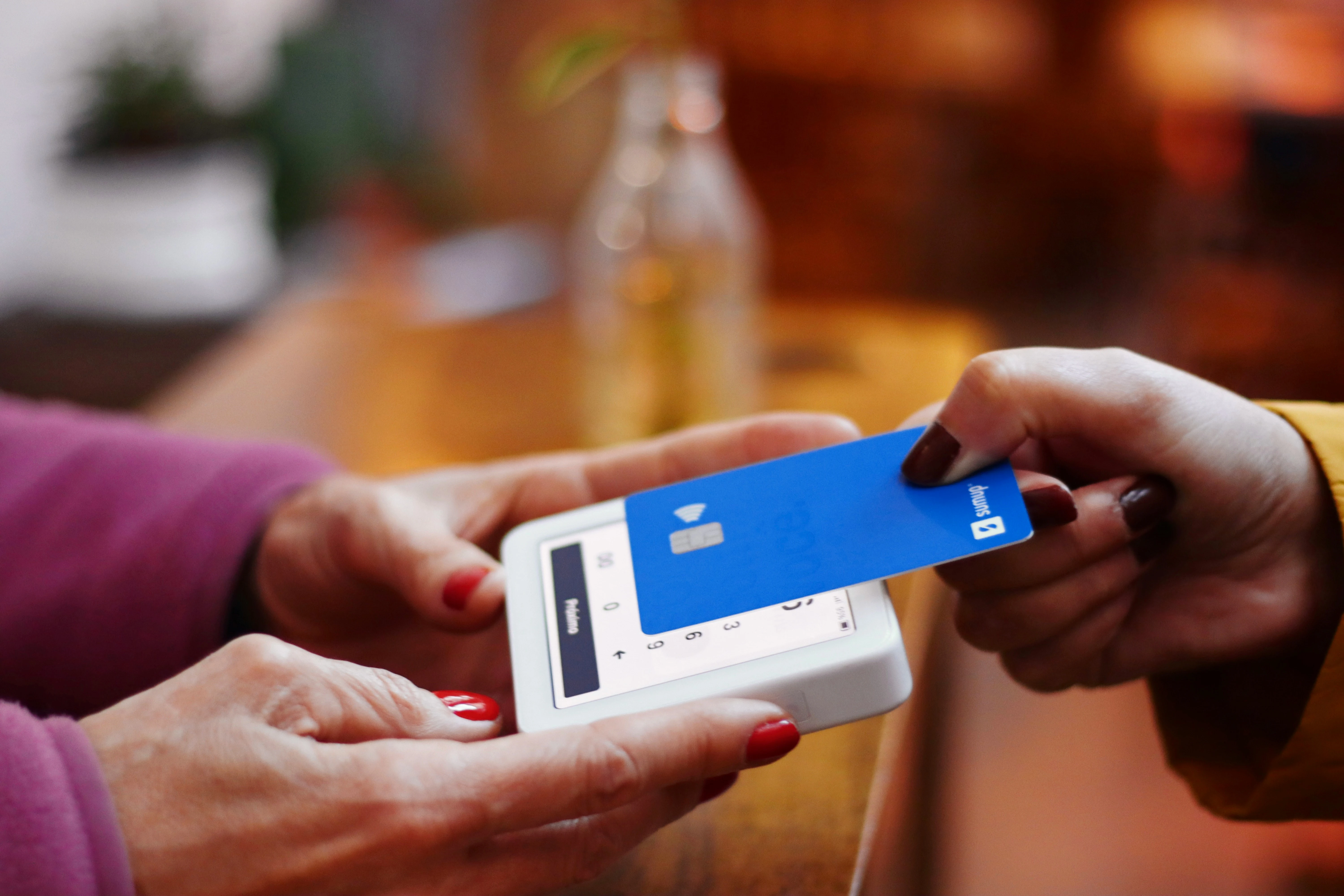 A customer making a contactless payment with a blue card using a mobile card reader.
