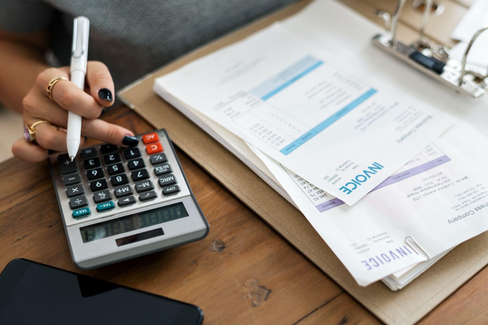Woman using a calculator, looking at invoices.