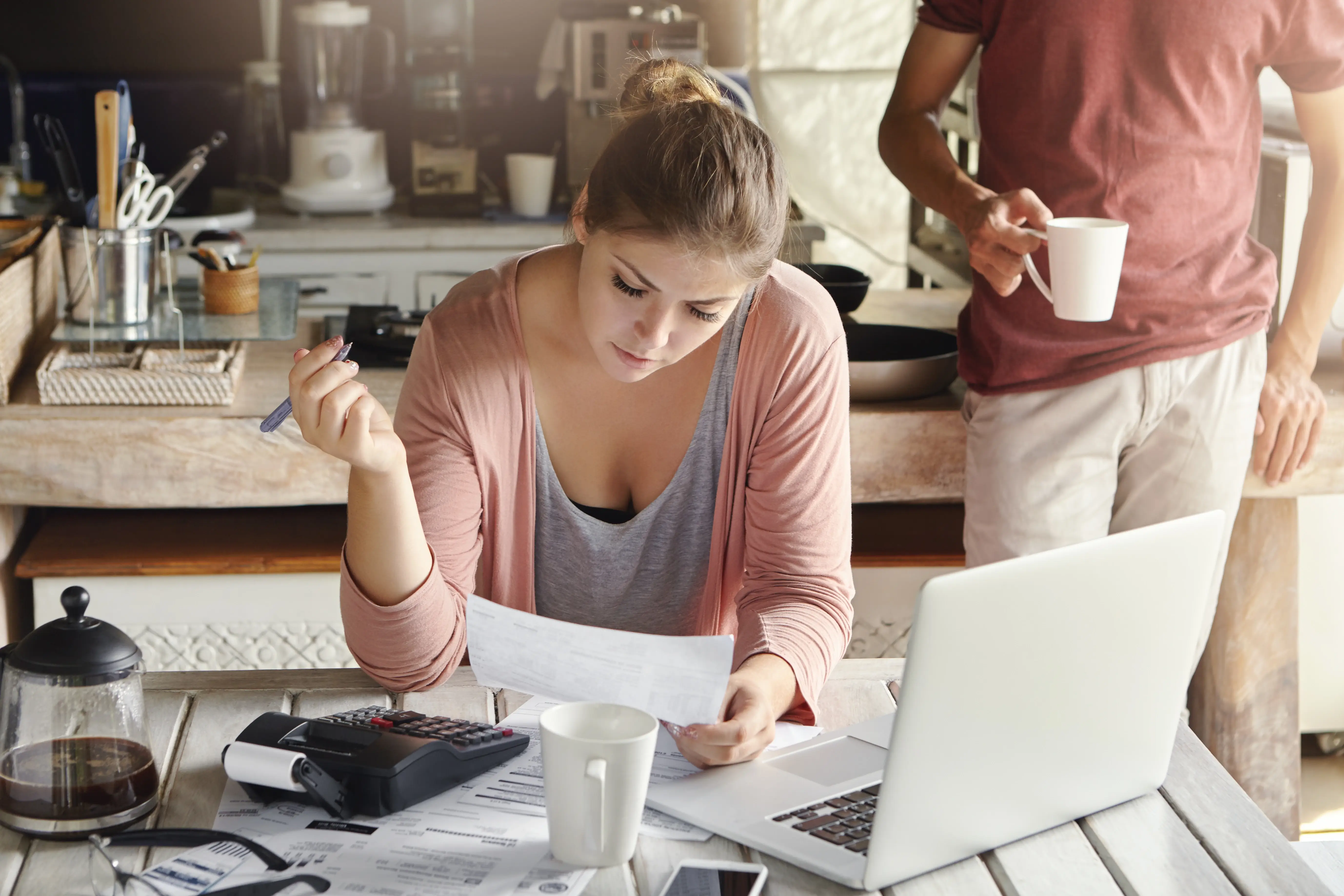 Business owner looking at invoicing and expenses paperwork next to her laptop