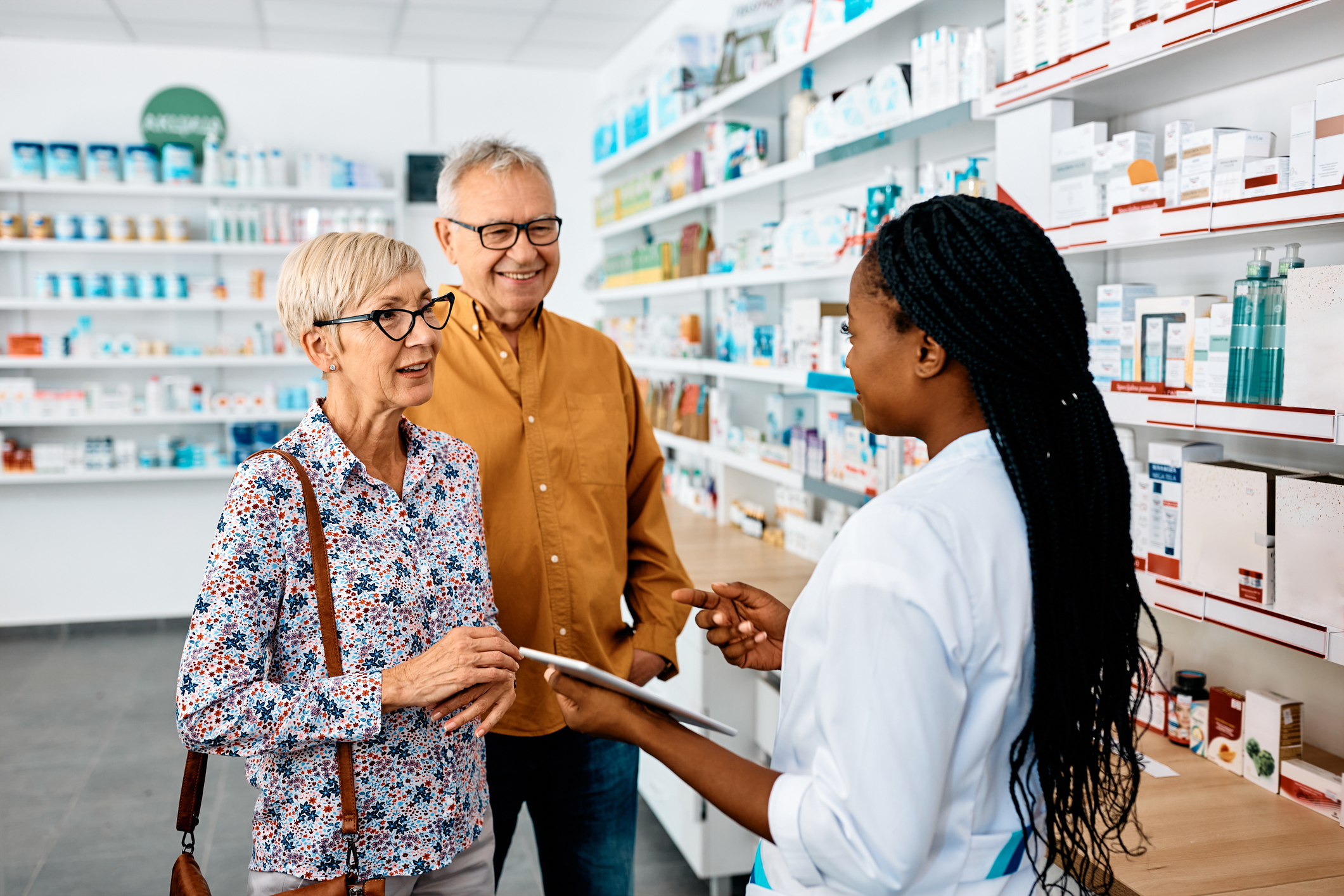 Une pharmacienne conseille deux patients dans son officine