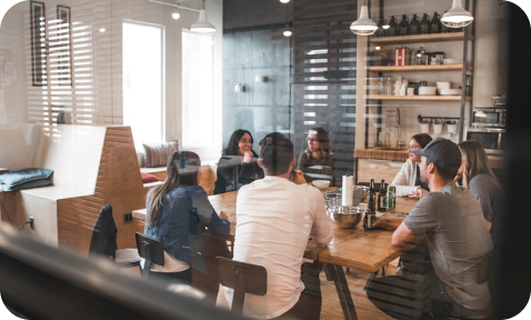 A group of people sitting around a wooden table.