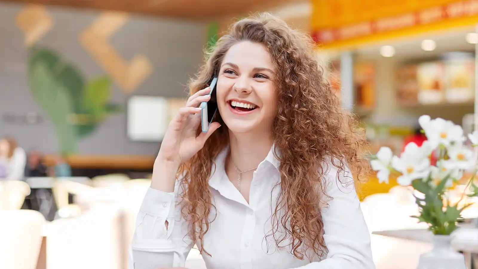A smiling customer talking on the telephone with a conversational AI agent.