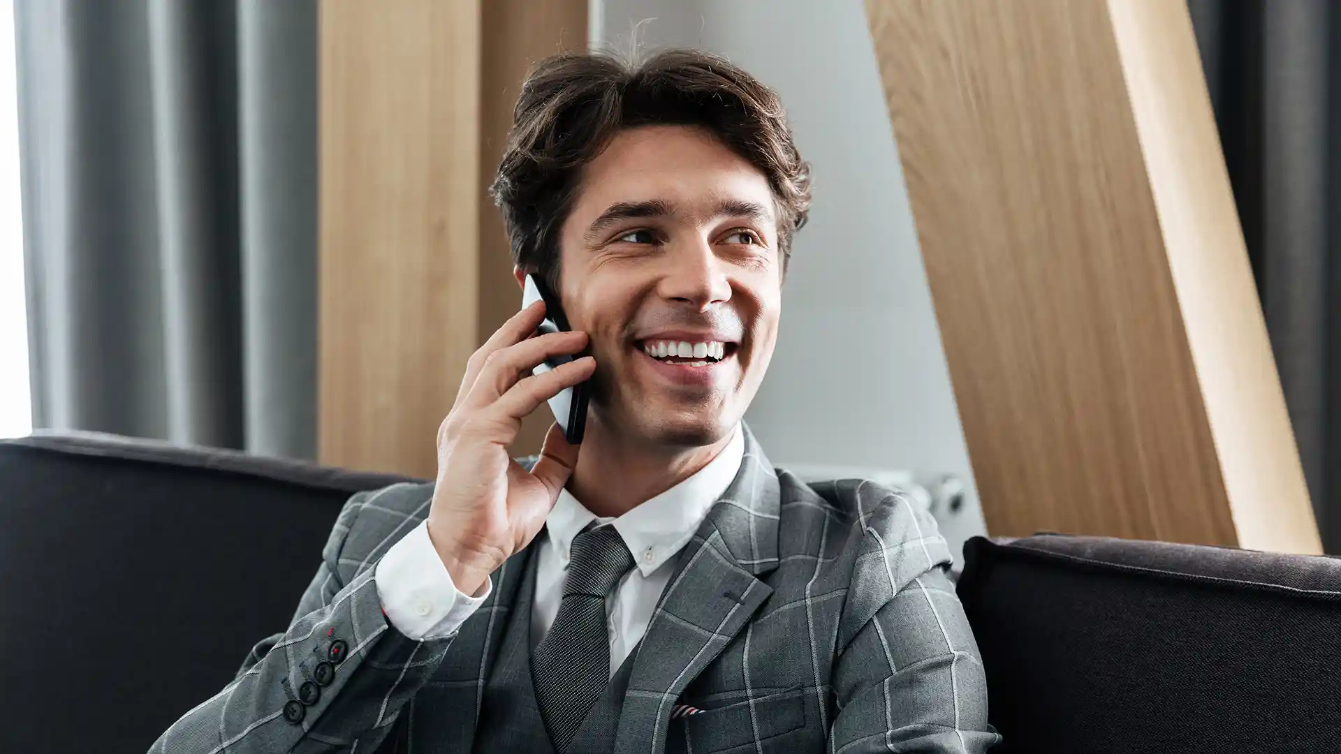 A smiling customer talking on the phone with a voice agent.