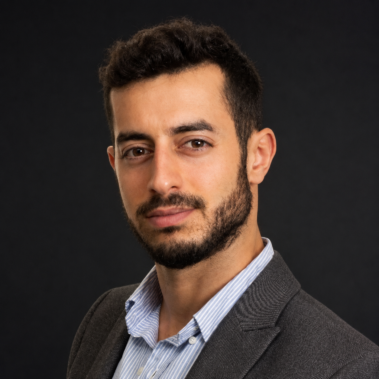 Professional headshot of Ohad Navon, Co-founder and CEO at Minded, wearing a dark blazer and light blue striped shirt against a dark background.