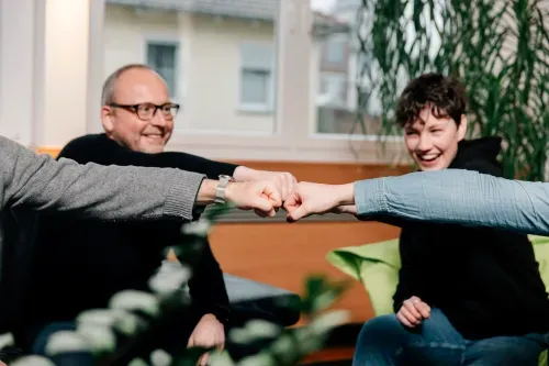 Fröhliches Team streckt die Fäuste in der Mitte zusammen, Teamarbeit