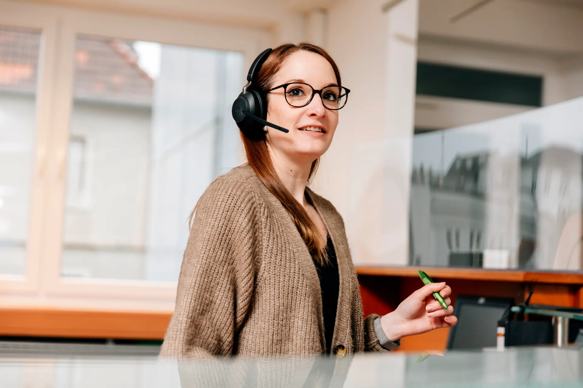 Frau mit Headset und Stift in der Hand