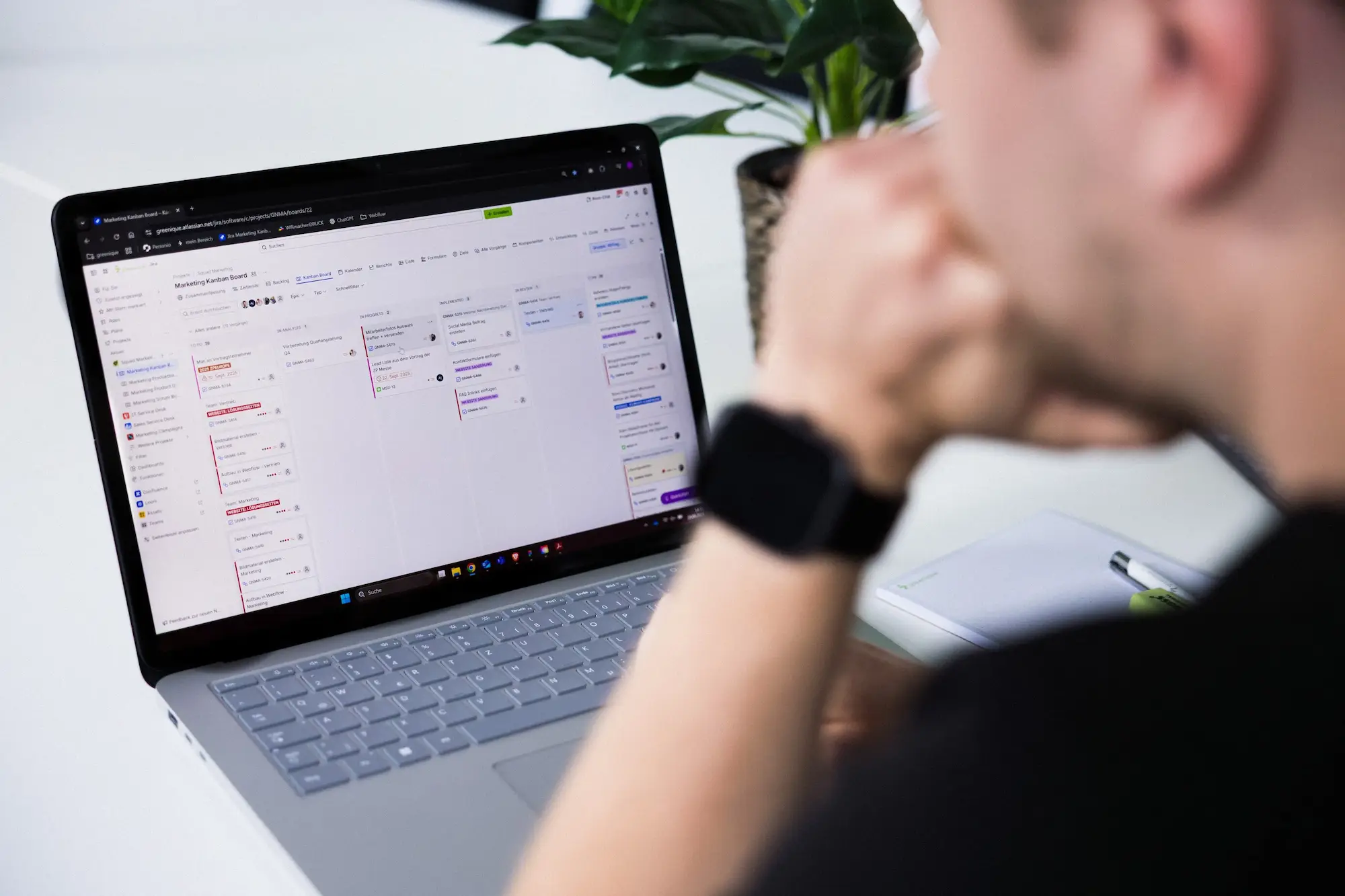 Person sitzt vor einem Notebook und schaut auf den Bildschirm.