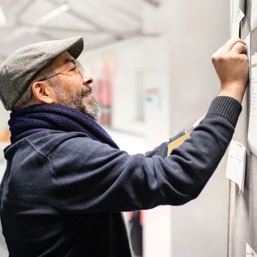 Mann pinnt Zettel an Wand.