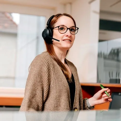 Frau mit Headset hält einen grünen Stift in der Hand.