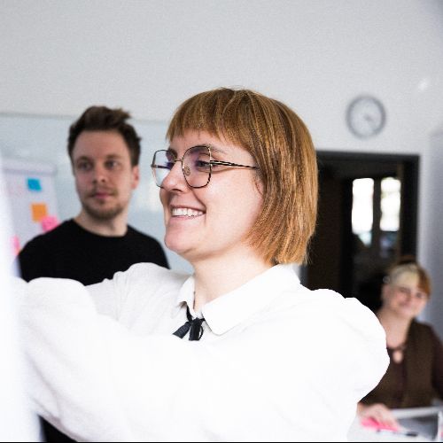 Mehrere Personen schauen auf eine Flipchart.