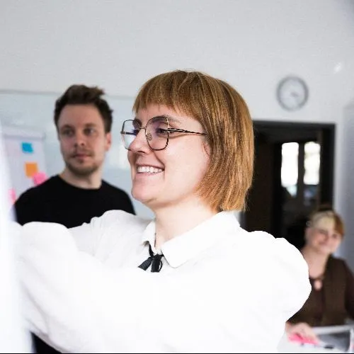 Mehrere Personen schauen auf eine Flipchart.