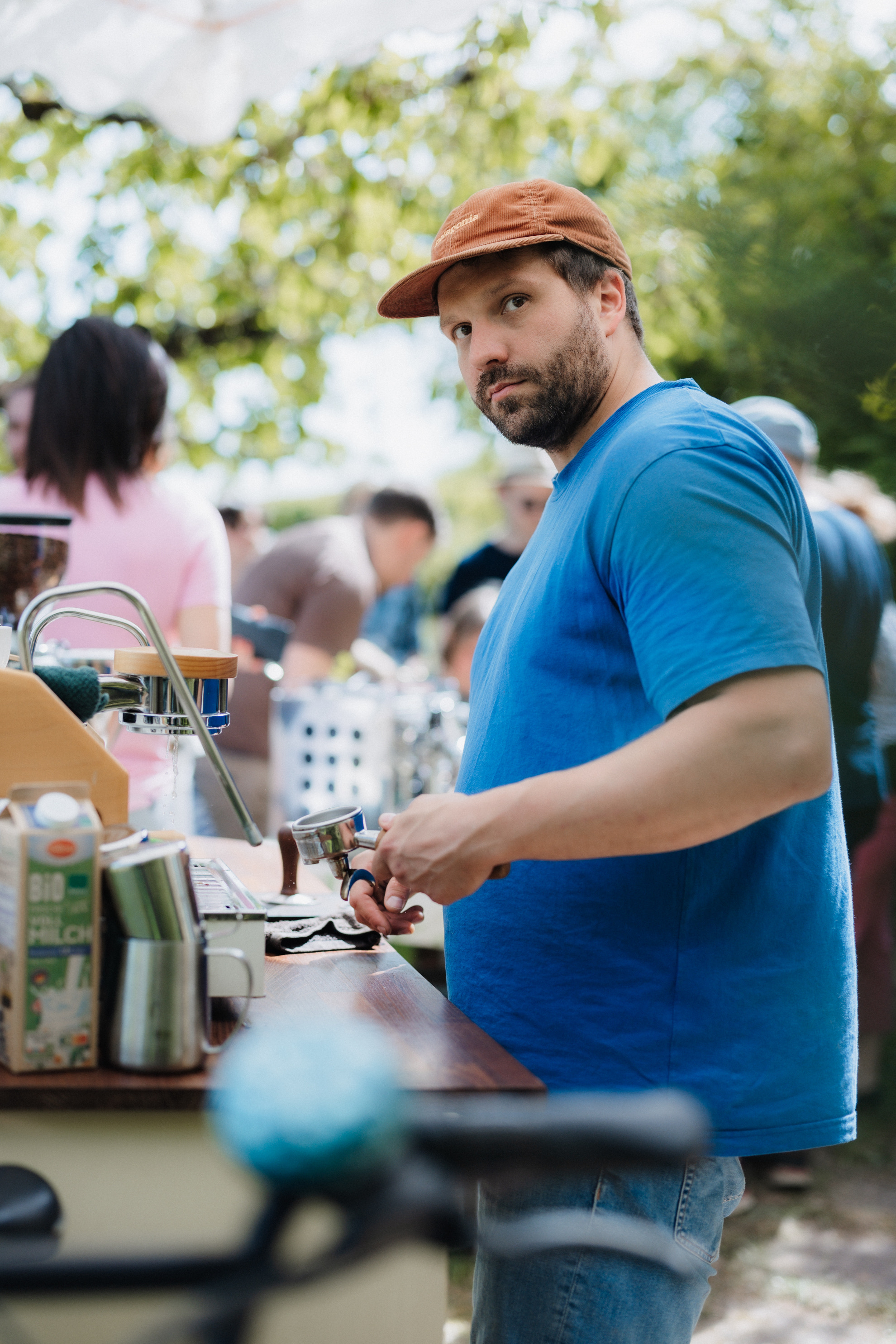 Mann genießt einen Espresso in der Sonne, umgeben von grünen Pflanzen.