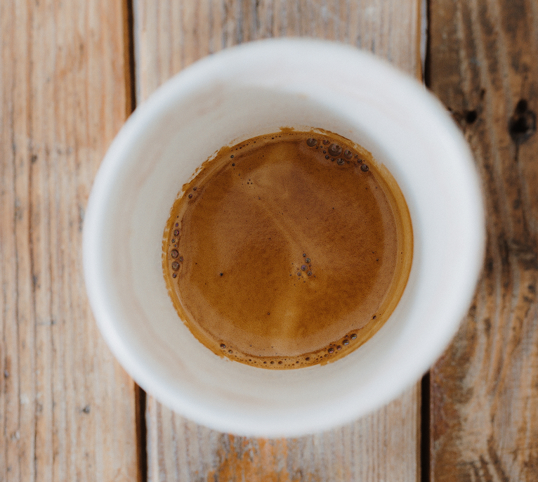 Top view of a cup of espresso on a wooden surface.