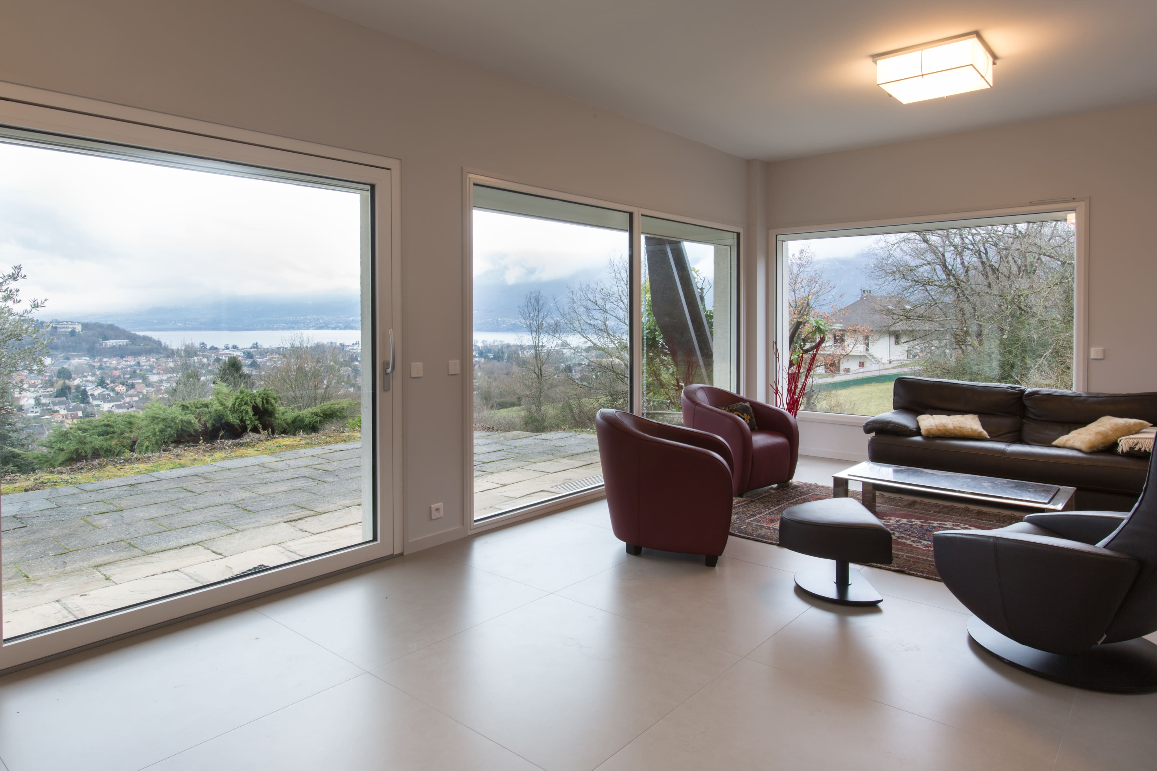 Baies vitrées en PVC installées dans un salon avec vue sur Annecy et le lac