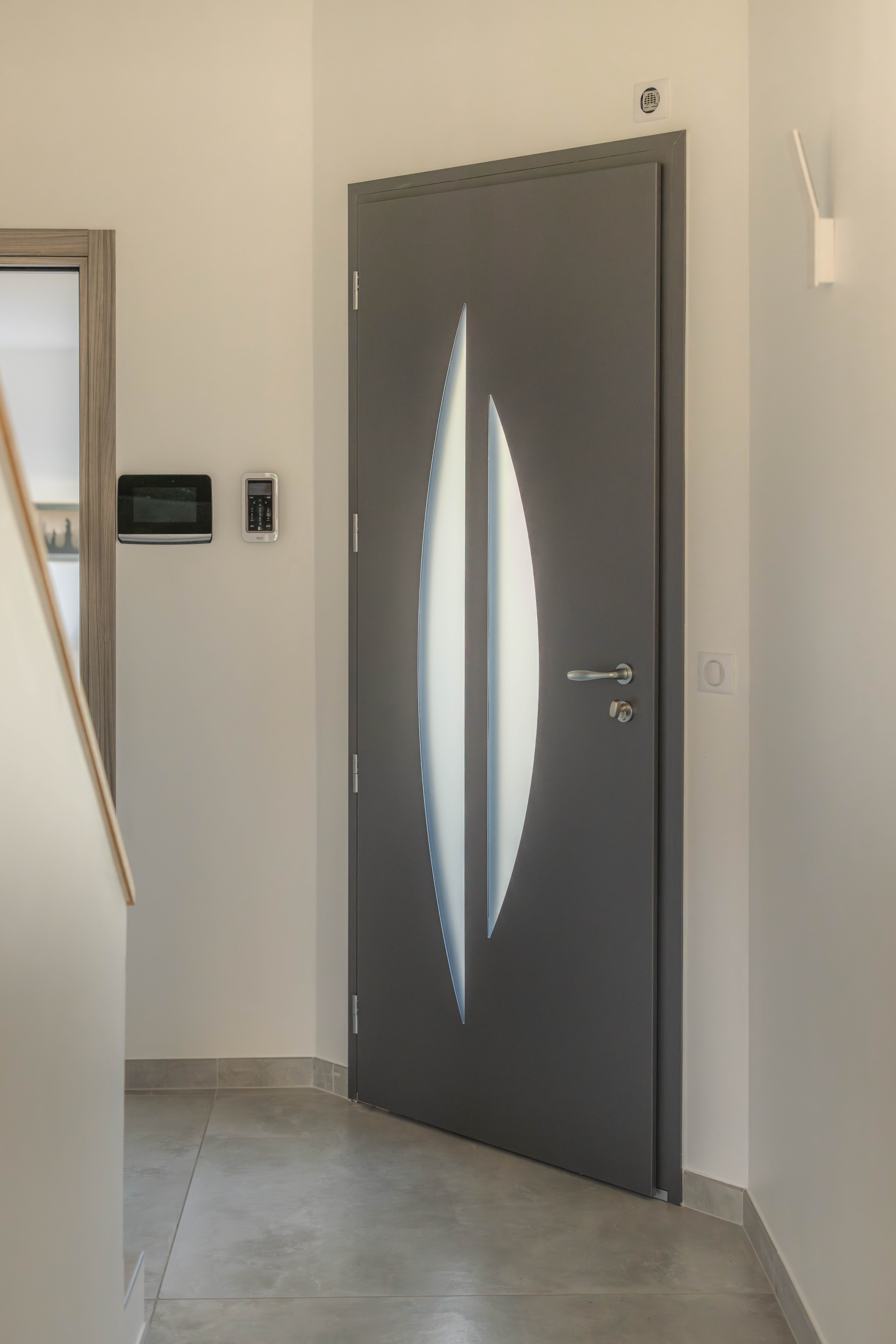 Vue intérieure d’une porte d’entrée design avec insert vitré dans une construction neuve