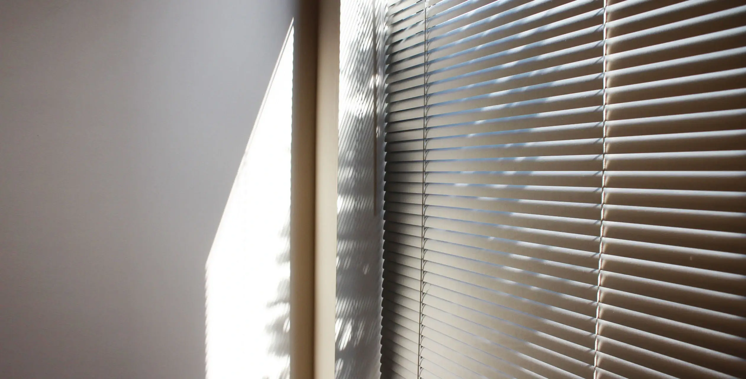 The image appears to be a close-up shot of an air conditioning unit mounted in a wall. The wall is visible on the left side of the image, and the air conditioner takes up the majority of the view with its horizontal grille and frame.