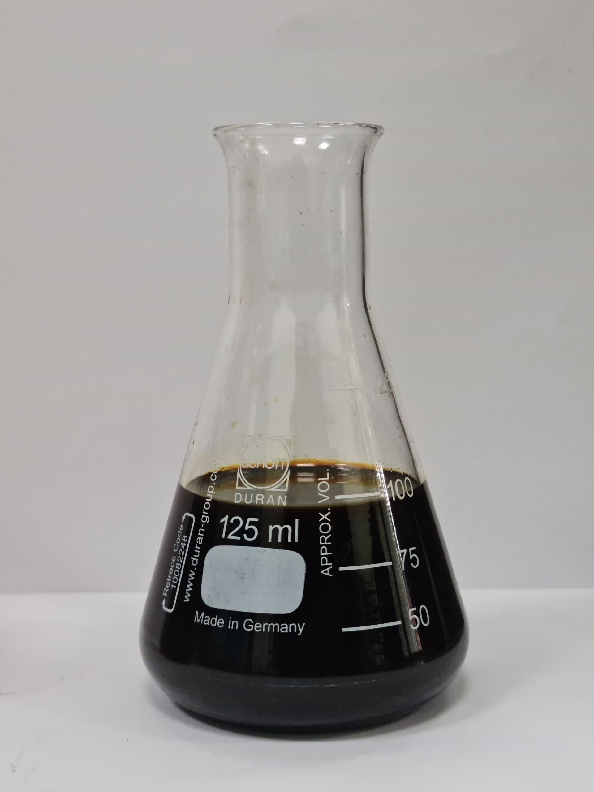 Pyrolysis oil sample in lab glassware, a circular fuel solution recovered from end-of-life tires