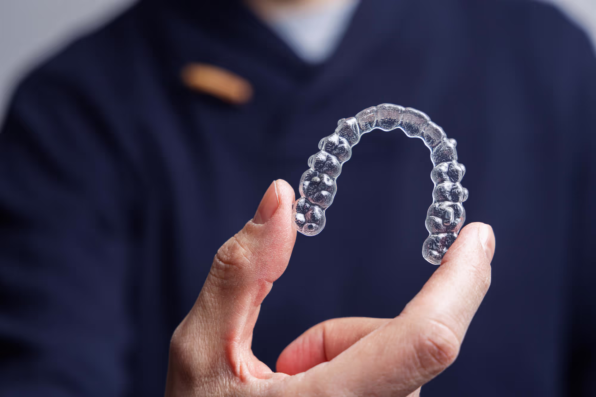 dentist holding an Invisalign clear aligner