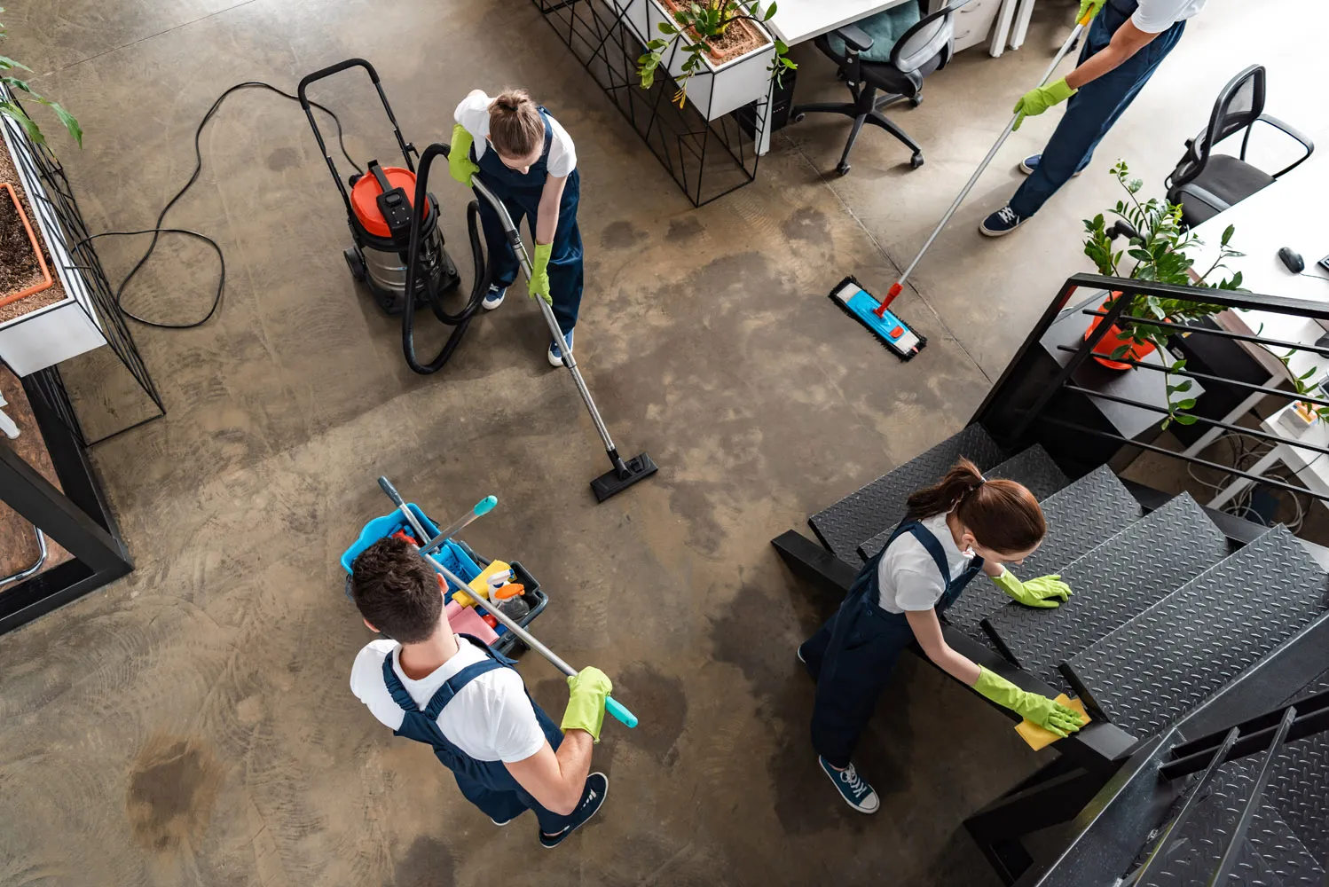 Commercial cleaning team vacuuming floors, mopping walkways, and wiping stair rails in a modern office during office cleaning and janitorial services.