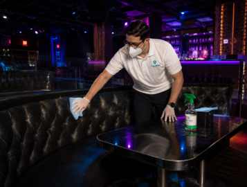 CleanWise Solutions nightclub cleaning worker deep cleaning a VIP booth in a nightlife venue.
