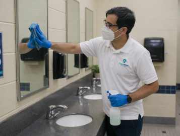 CleanWise Solutions educational facility cleaning worker sanitizing a school restroom.
