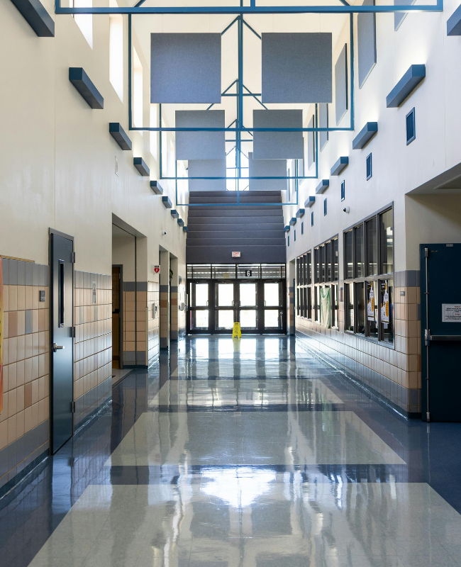 Clean, polished school hallway with reflective floors and bright common areas, representing educational facility cleaning and commercial janitorial services.