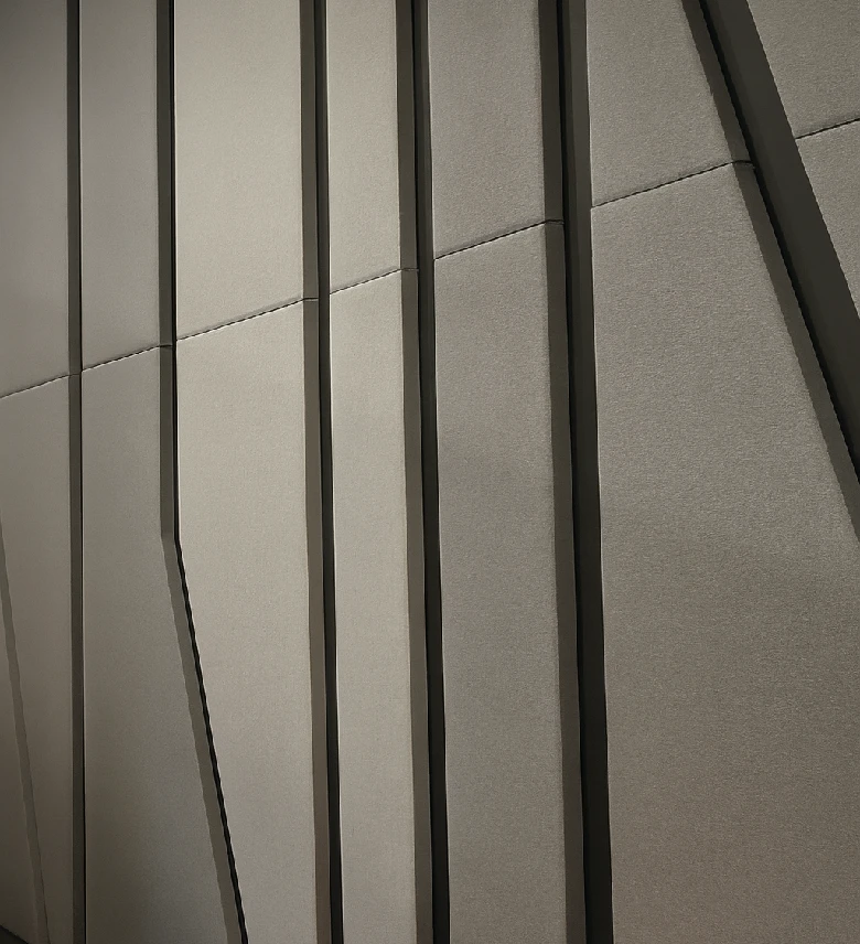 Paneles absorbentes de sonido tapizados en tonos grises con líneas y cortes geométricos.