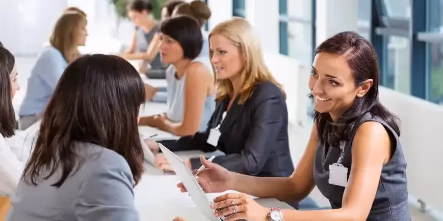 Professionals seated across tables engaging in one-on-one career discussions, with laptops and notepads in use at a career expo.
