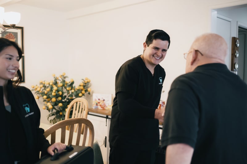 In Motion Dentists Team greeting elderly patient in their dining room