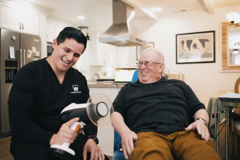 Dentist demonstrating dental device or model to senior patient in home setting